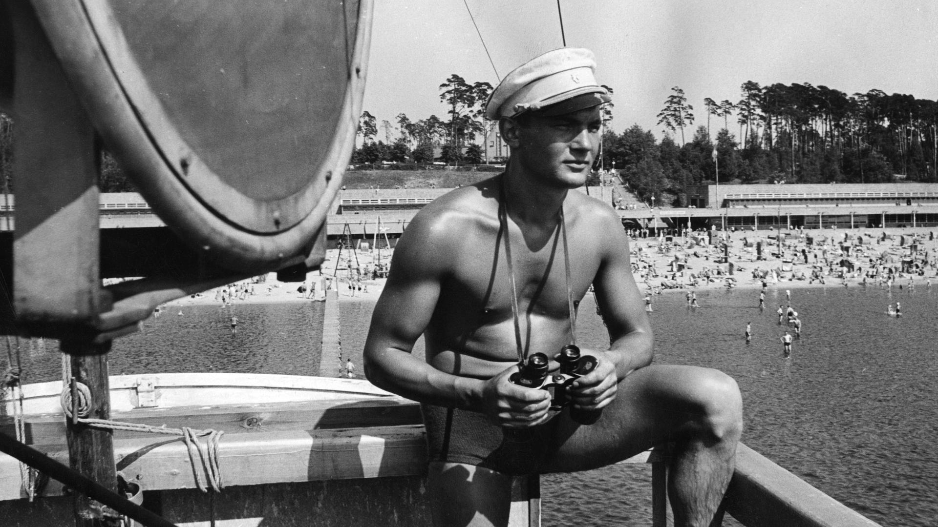 Mit einem Fernglas und Mütze steht der der Bademeister auf seinem Aussichtspunkt und bewacht die Badegäste des Wannsee Strandbads. Mit einem Fernglas und Mütze steht der der Bademeister auf seinem Aussichtspunkt und bewacht die Badegäste des Wannsee Strandbads.