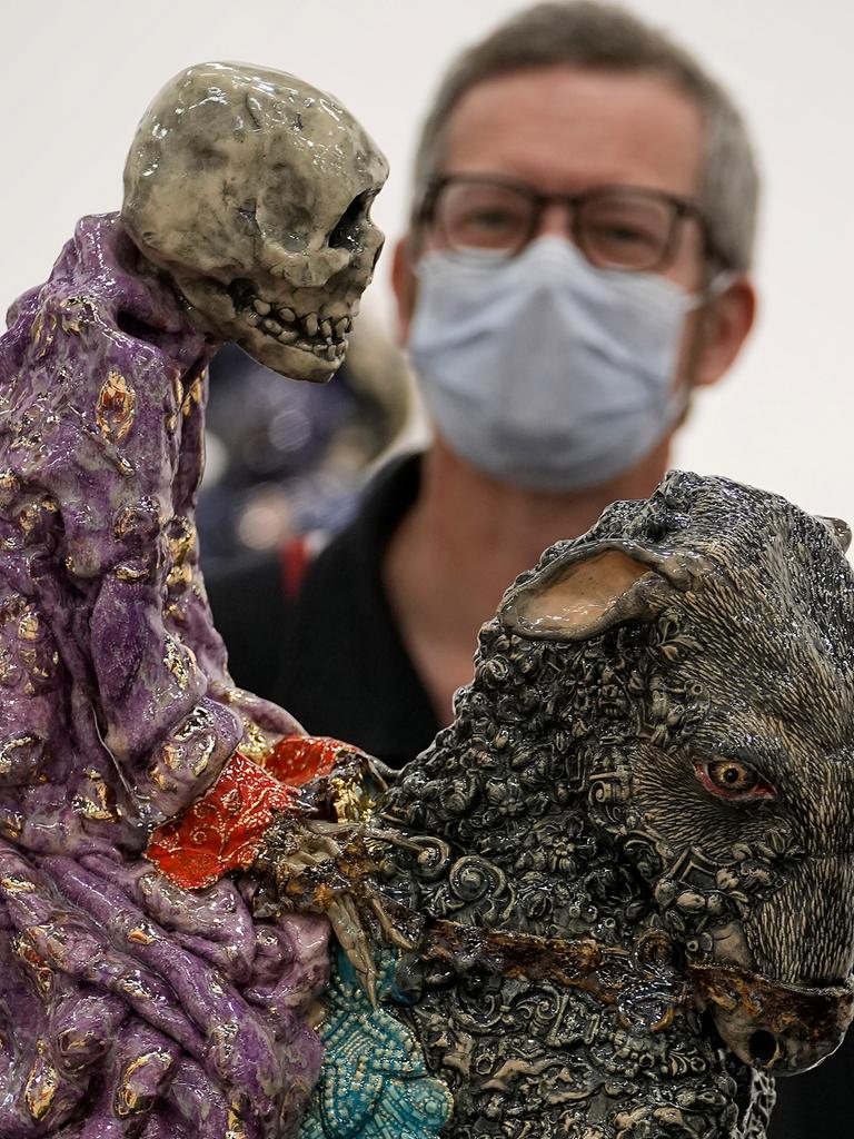 Ein Besucher mit Maske betrachtet auf der Art Cologne eine Arbeit von Carolein Smit aus den Niederlanden. Es ist ein auf einer Ziege reitendes Skelett.