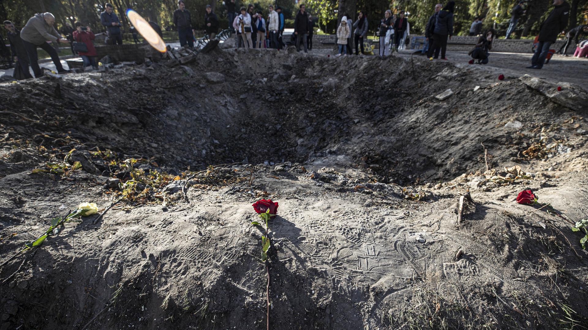 An einem Bombenkrater legen die Bewohner von Kiew Blumen ab