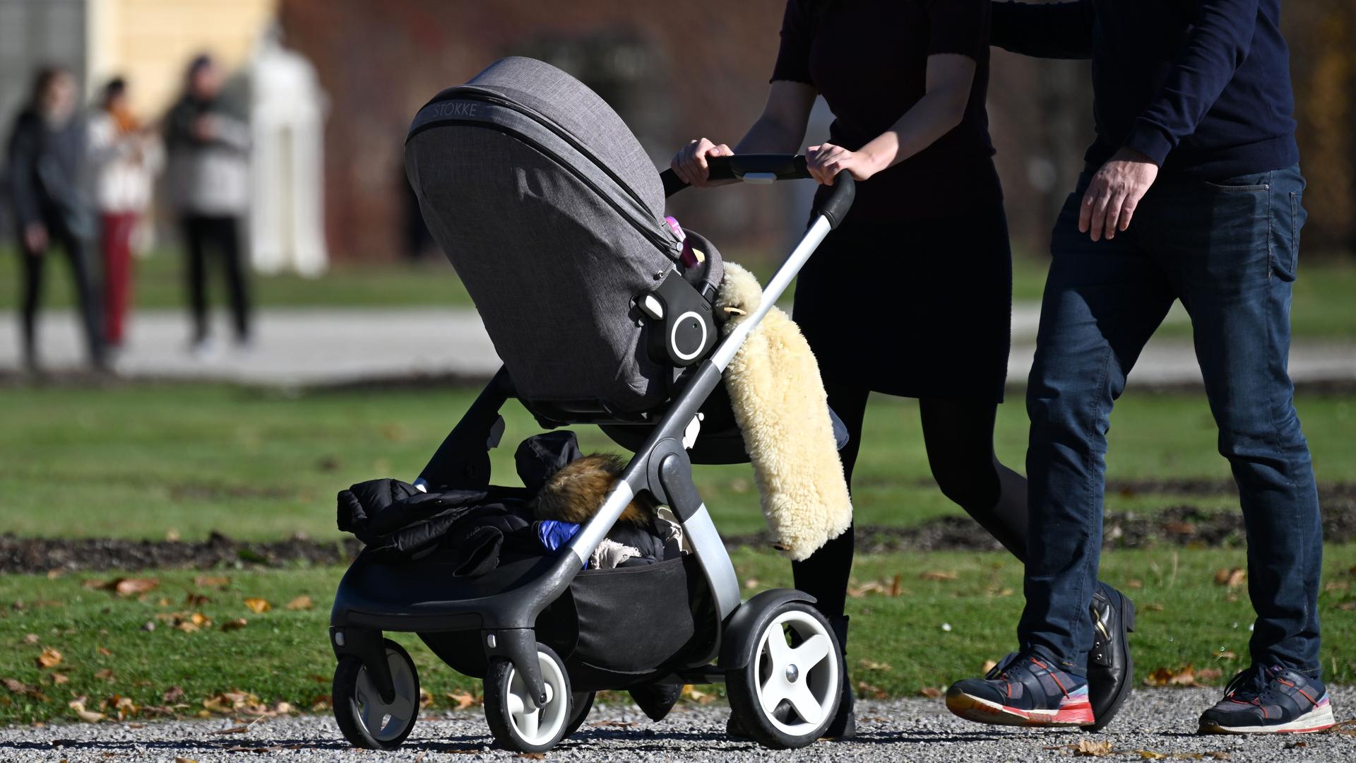  Eine Familie geht mit einem Kinderwagen spazieren