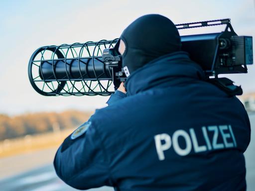 Polizeibeamter mit Sturmhaube hält einen Gewehr-förmigen Jammer auf der Schulter, der Polizist gehört zur neuen Drohnenabwehreinheit der Bundespolizei.