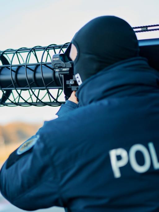 Polizeibeamter mit Sturmhaube hält einen Gewehr-förmigen Jammer auf der Schulter, der Polizist gehört zur neuen Drohnenabwehreinheit der Bundespolizei. Polizeibeamter mit Sturmhaube hält einen Gewehr-förmigen Jammer auf der Schulter, der Polizist gehört zur neuen Drohnenabwehreinheit der Bundespolizei.
