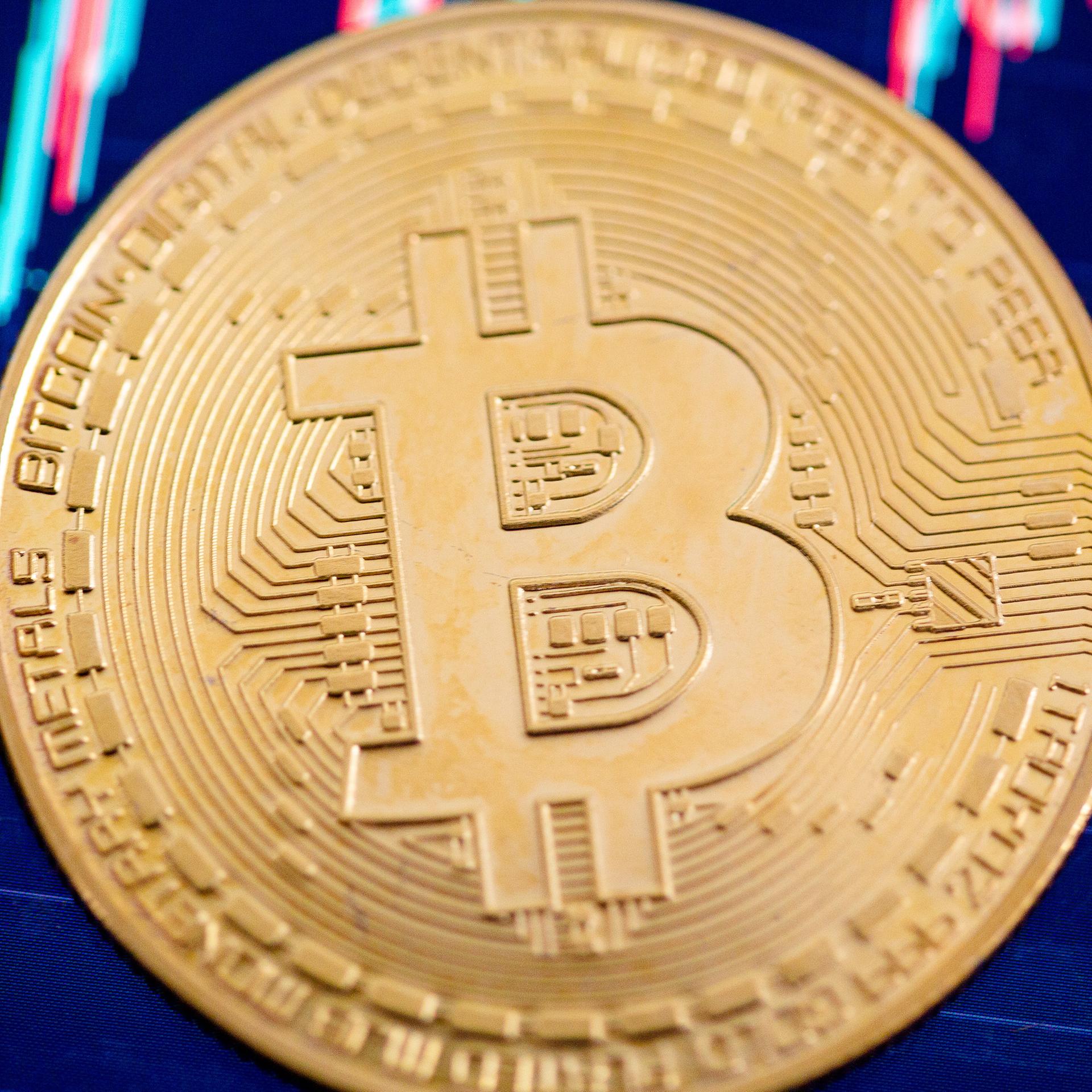 Eine Bitcoin-Münze liegt auf einem Bildschirm, der den Bitcoin - US-Dollar Kurs zeigt. Eine Bitcoin-Münze liegt auf einem Bildschirm, der den Bitcoin - US-Dollar Kurs zeigt.