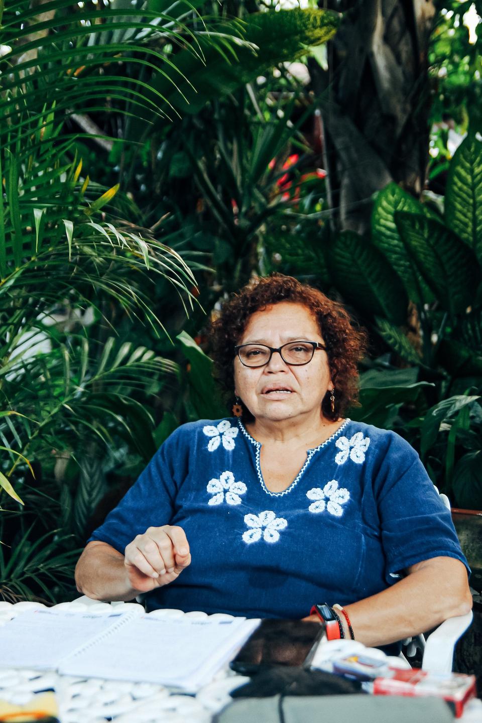 Die Frauenrechtlerin Morena Herrera sitzt an einem Schreibtisch im Garten.