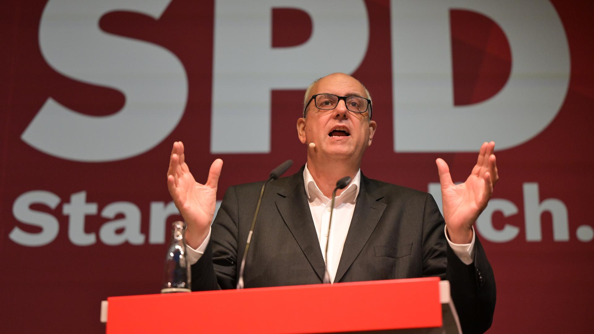 Das Foto zeigt Andreas Bovenschulte (SPD), Bürgermeister und Senatspräsident von Bremen, während des Landesparteitags der SPD. Ers teht an einem Redner-Pult und gestikuliert mit seinen Händen.