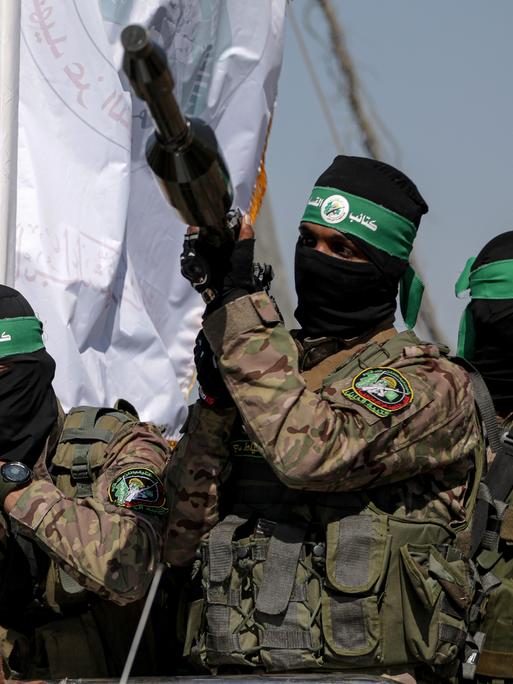 Mehrere Kämpfer der Hamas halten Waffen in die Höhe, ihre Gesichter sind vermummt.