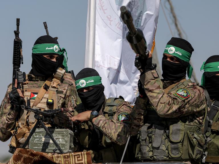 Mehrere Kämpfer der Hamas halten Waffen in die Höhe, ihre Gesichter sind vermummt.