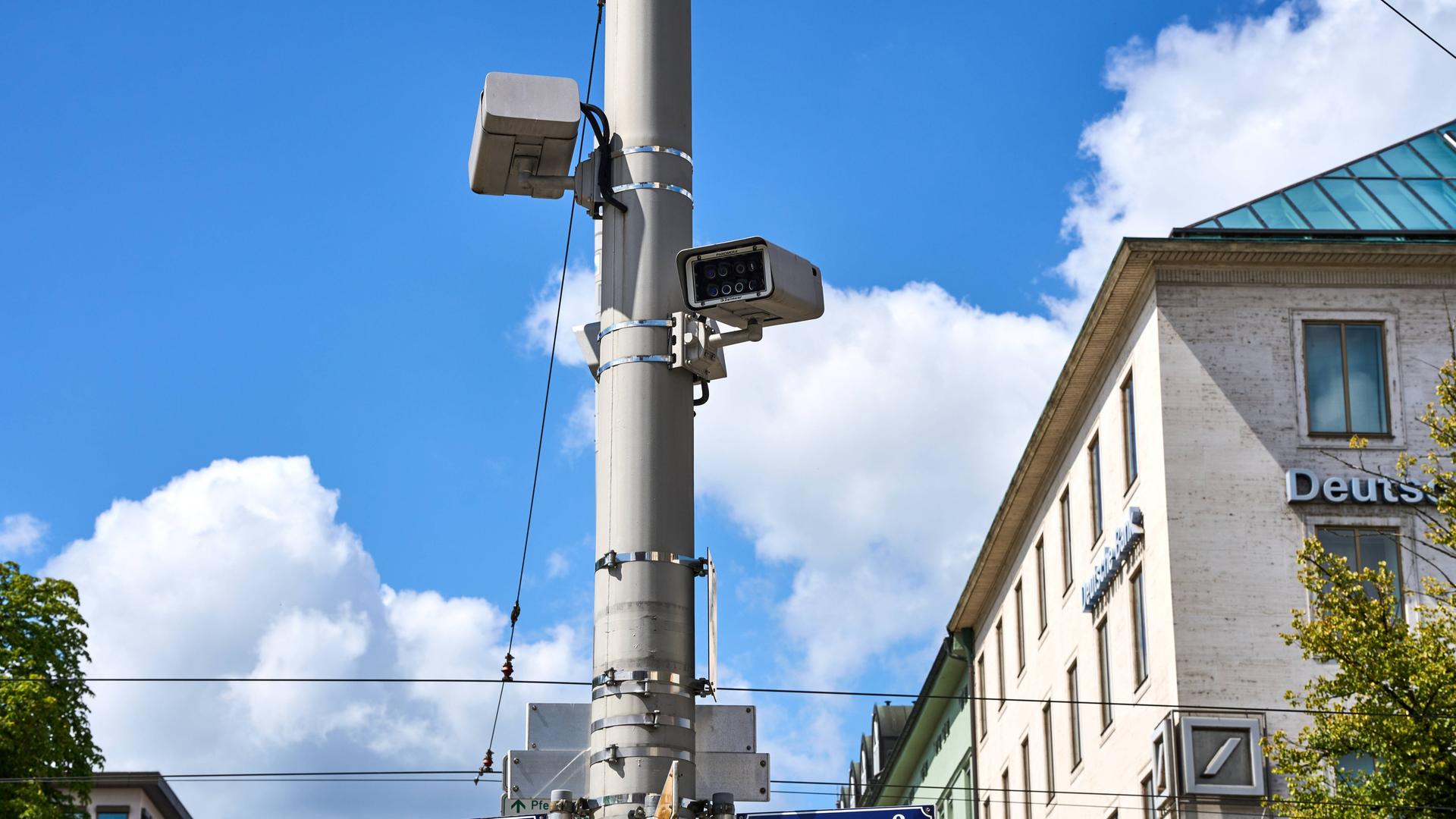 Blick auf einen Lichtmast mit Kameras, die eine Straßenkreuzung überwachen.