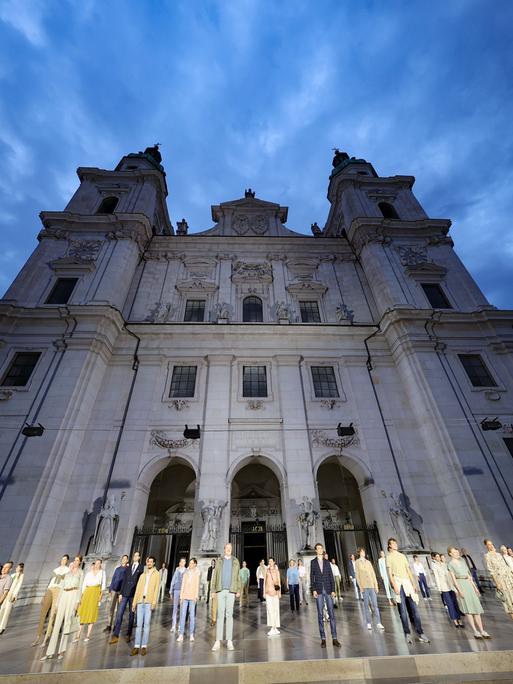 Das Ensemble der Jedermann-Inszenierung steht bei einer Probe auf dem Salzburger Domplatz, dahinter der Dom.