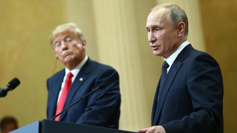 US-Präsident Trump und Russlands Präsident Putin geben gemeinsam eine Pressekonferenz: Putin steht am Redepult und spricht, Trump dreht sich zu ihm und hört zu.