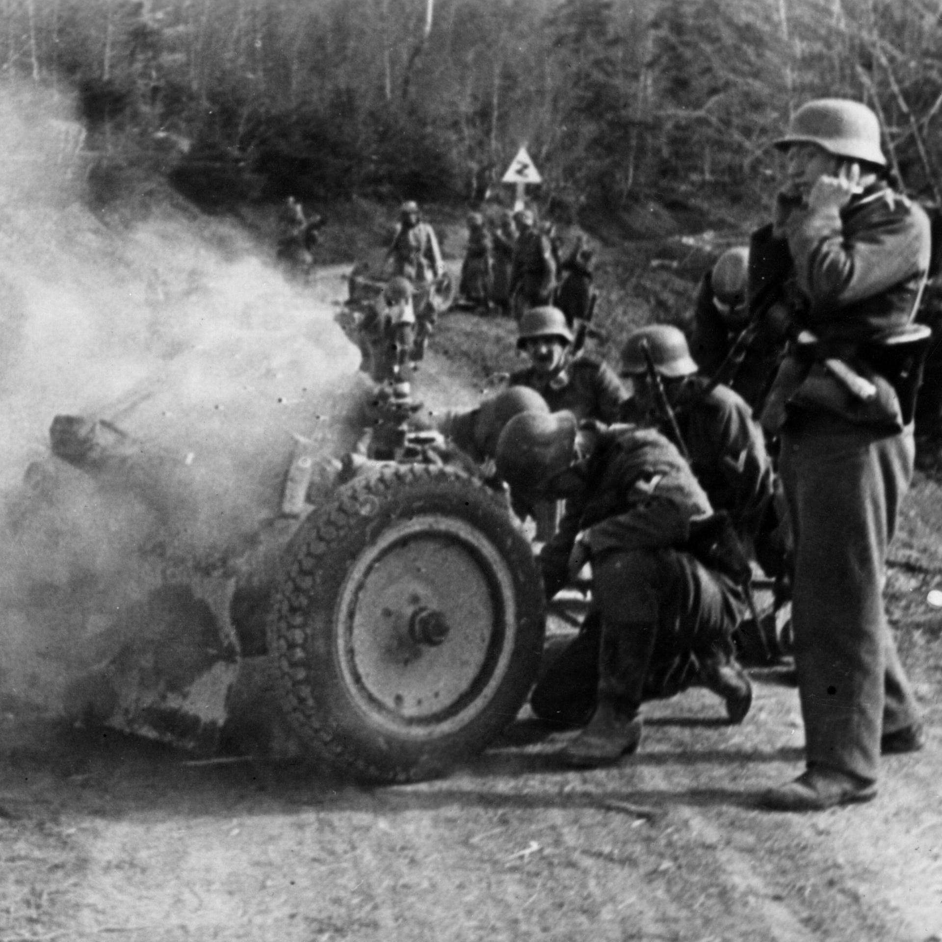 Soldaten der Deutschen Wehrmacht feuern ein Infanteriegeschütz auf einer Paßstraße ab.
