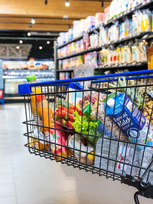 Ein Einkaufswagen mit verschiedenen Lebensmittel in einem Supermarkt.