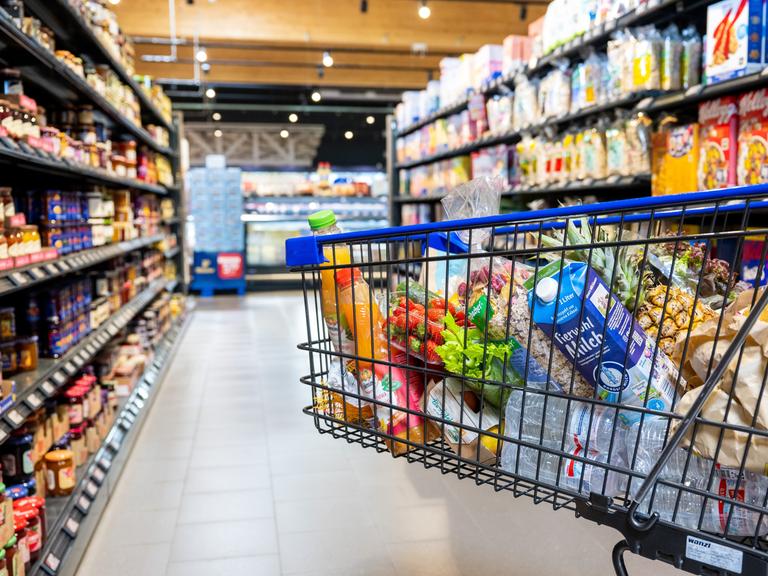 Ein Einkaufswagen mit verschiedenen Lebensmittel in einem Supermarkt.