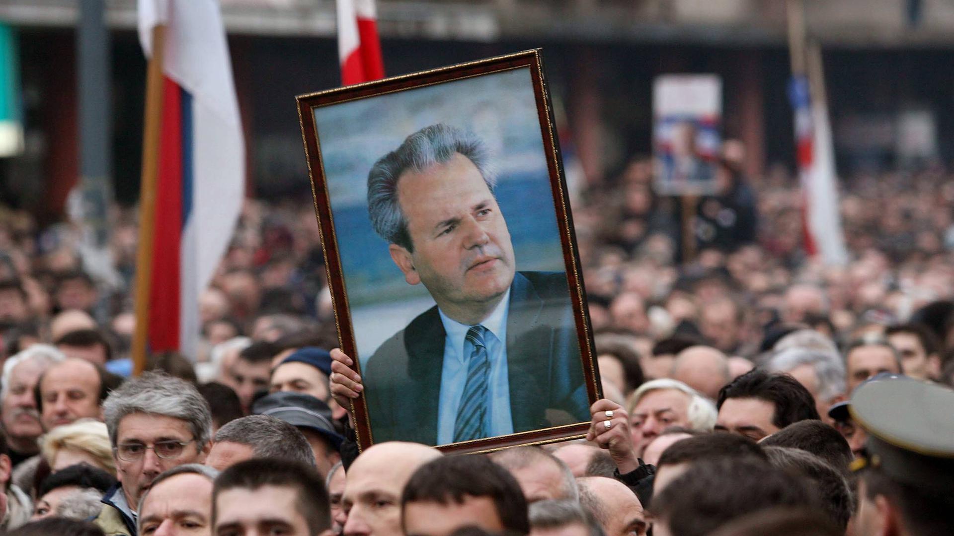 Bei einer Demonstration hält ein Mensch von Porträt von Slobodan Milosevic hoch