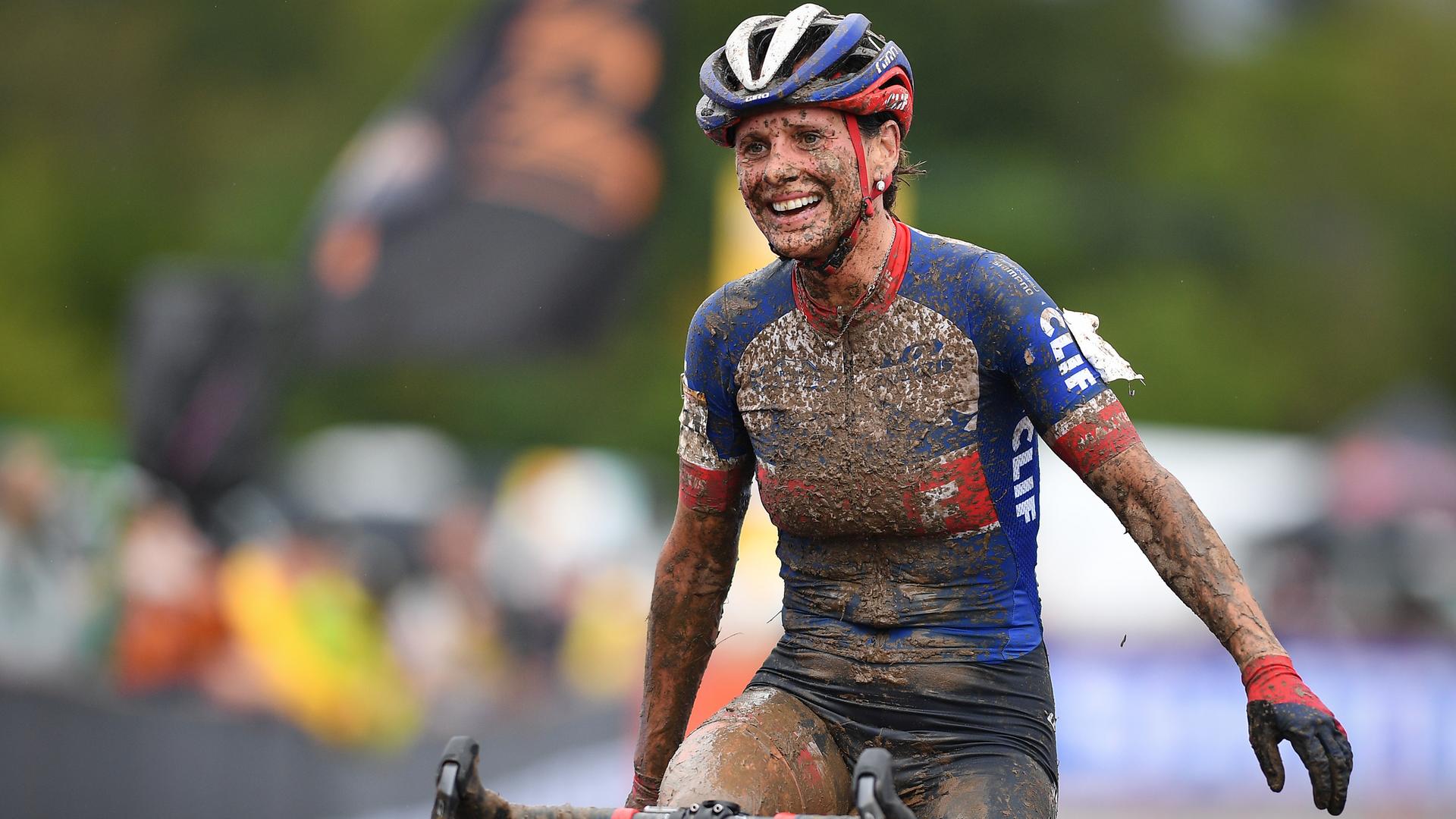 Die tschechische Radsportlerin und Langläuferin Katerina Nash fährt voll Matsch gespritzt aber lächelnd als Siegerin eines Cyclocross-Rennens über die Ziellinie