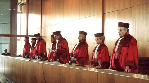 Richter und Richterin vom Bundesverfassungsgericht in roten Roben am Richtertisch Richter und Richterin vom Bundesverfassungsgericht in roten Roben am Richtertisch