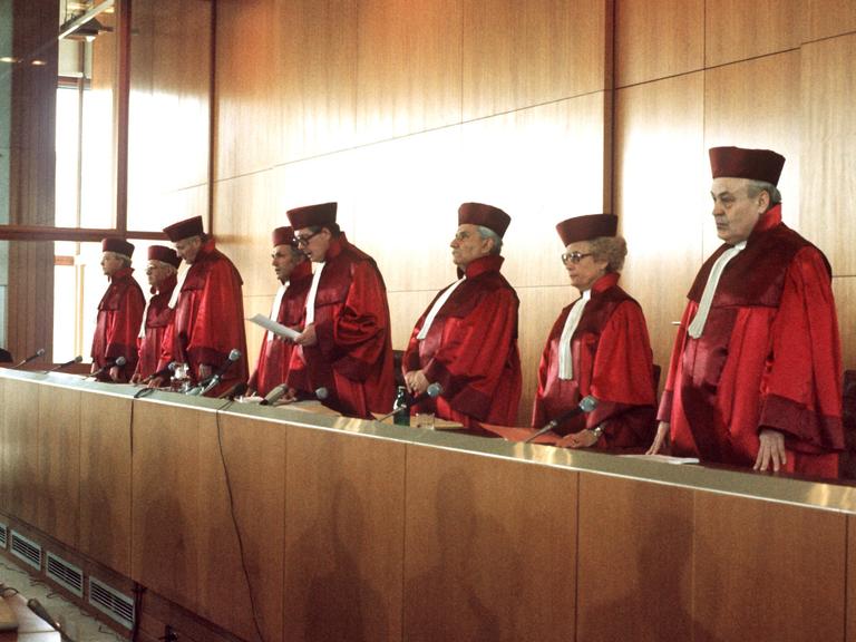 Richter und Richterin vom Bundesverfassungsgericht in roten Roben am Richtertisch