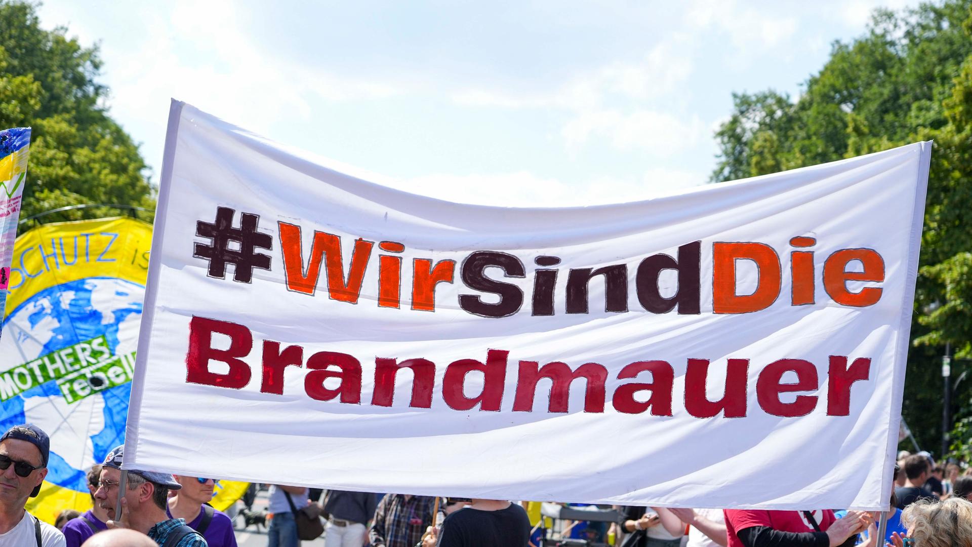 Demonstrierende in Berlin halten ein großes Transparent mit der Aufschrift "Wir sind die Brandmauer".