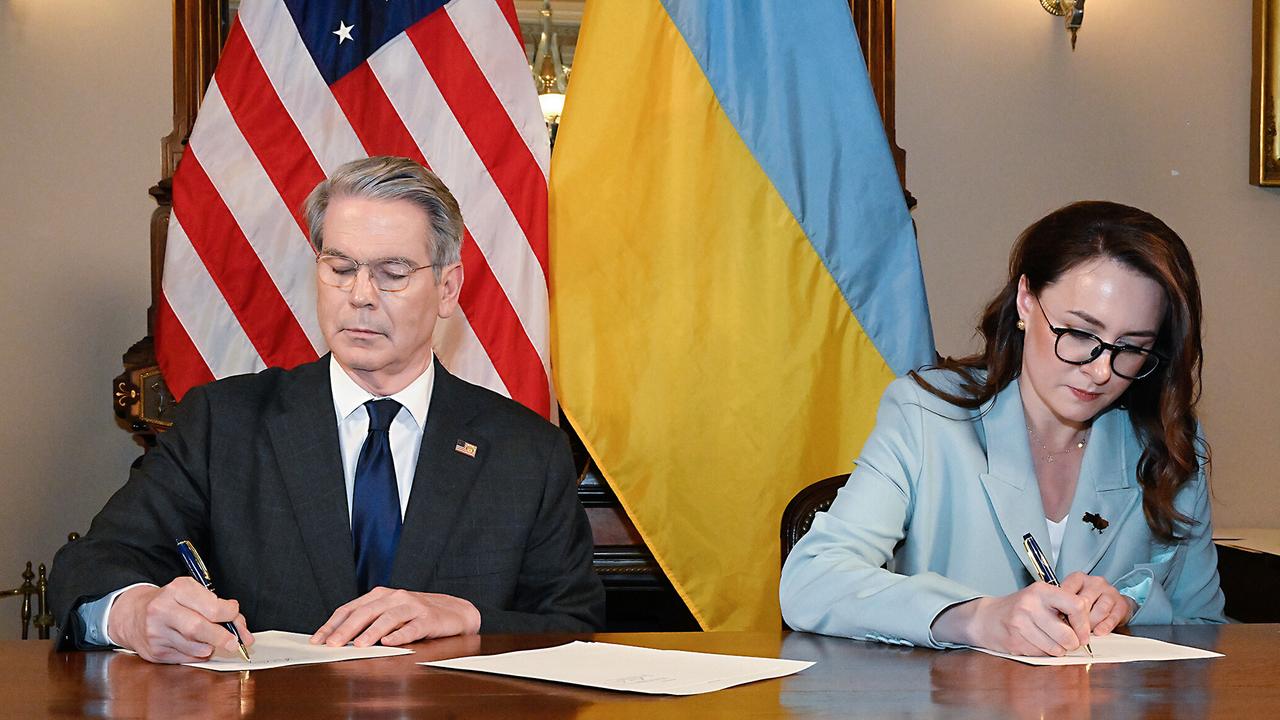 US-Finanzminister Bessent und die ukrainische Wirtschaftsministerin Swyrydenko unterschreiben das Rohstoffabkommen. Bessent (li) hat kurze graue Haare und sitzt vor der US-Flagge. Swyrydenko (re) vor einer ukrainischen Flagge.
