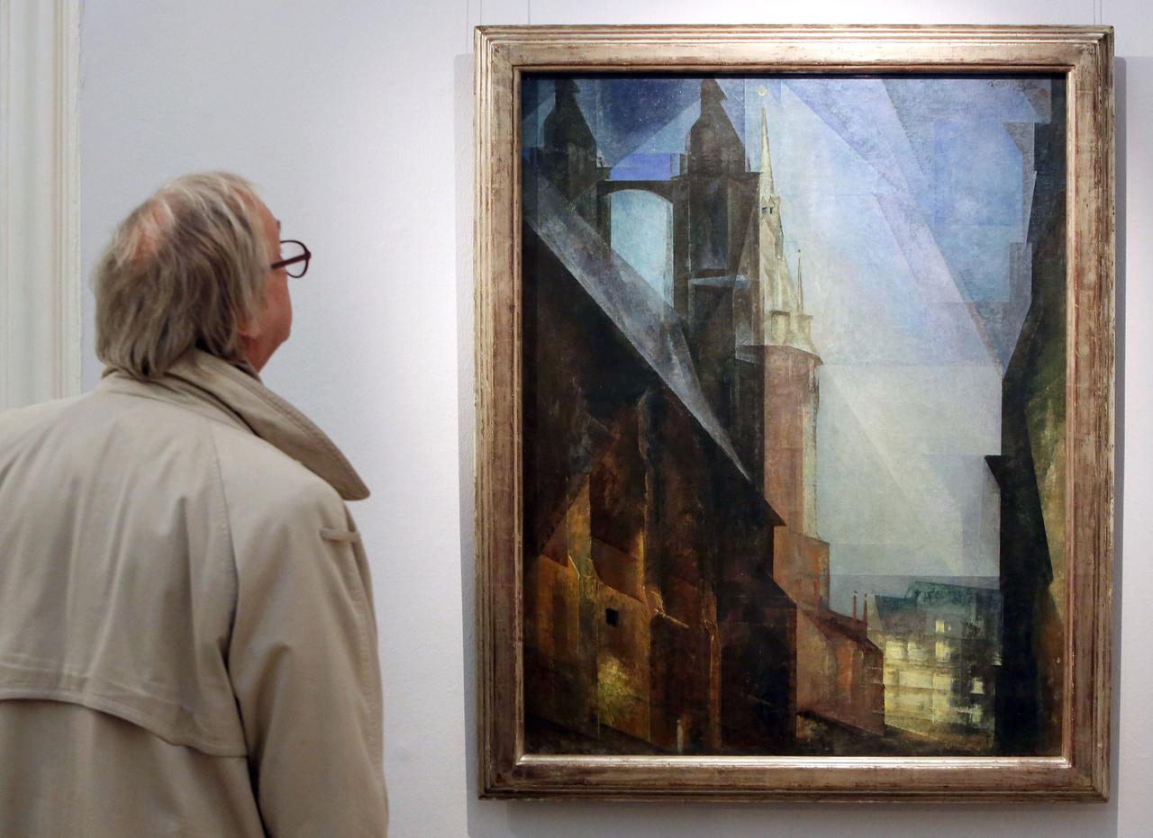 Ein Mann mit Brille steht vor einem Gemälde. Es zeigt eine Kirche mit zwei Türmen vor dunklem Nachthimmel.