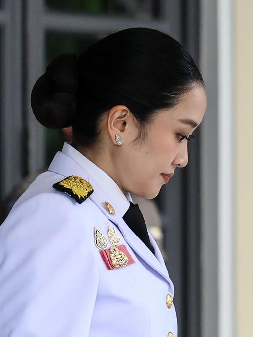 Paetongtarn Shinawatra verlässt in militärischer Uniform das Regierungsgebäude mit gesenktem Kopf. 