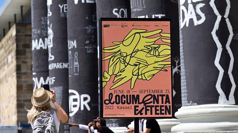 Eine Frau fotografiert die von Dan Perejovschi bemalten Säulen des Fridericianums auf der Documenta in Kassel. 