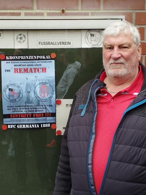 Heinz-Dietrich Kraschewski steht vor dem Plakat für das Spiel gegen Civil Service.
