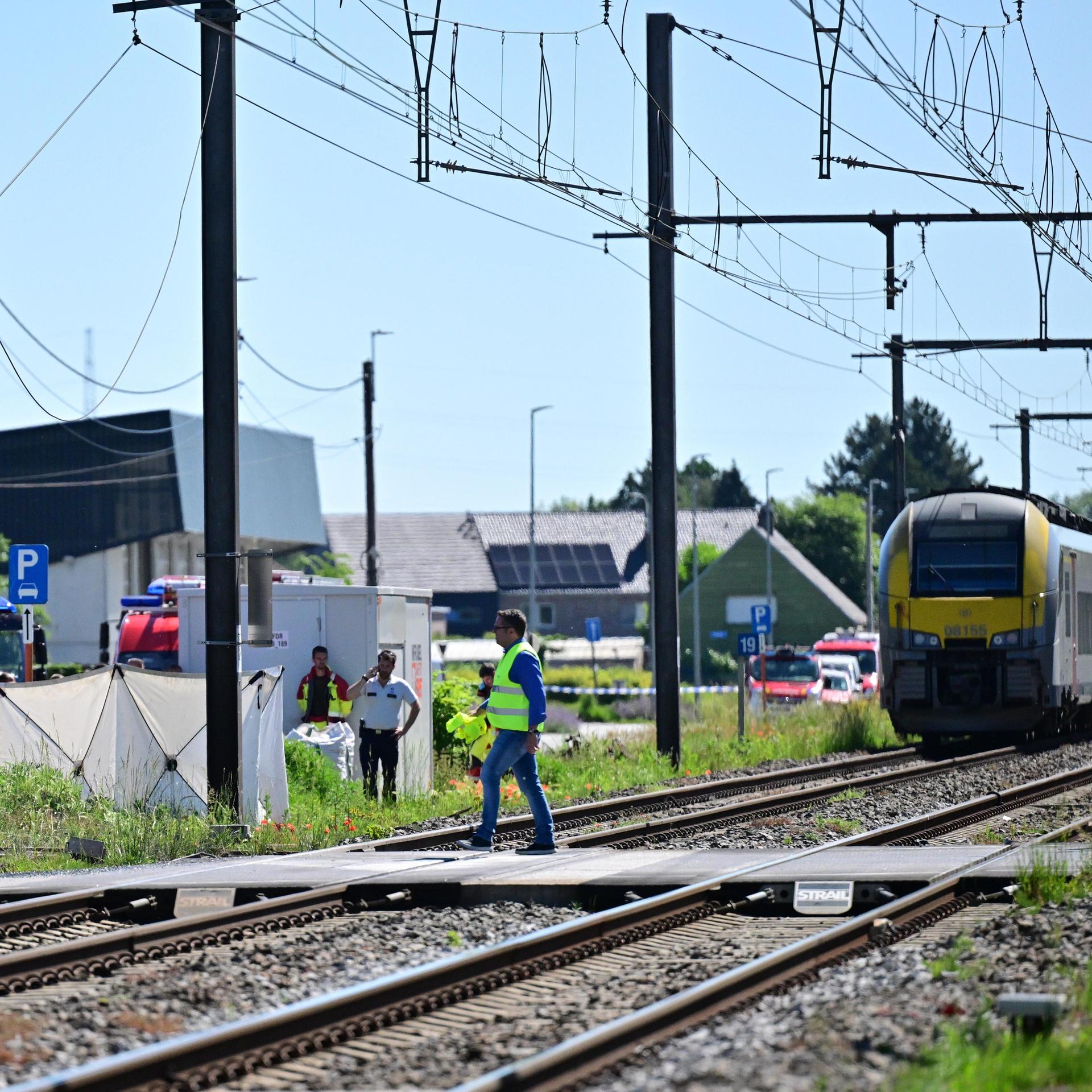 Beamte sichern die Unfallstelle; auf den Gleisen steht ein Regionalzug