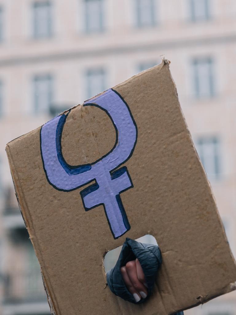 Eine Hand, die ein abgeknicktes Transparent mit dem violetten Symbol für Frauen hält