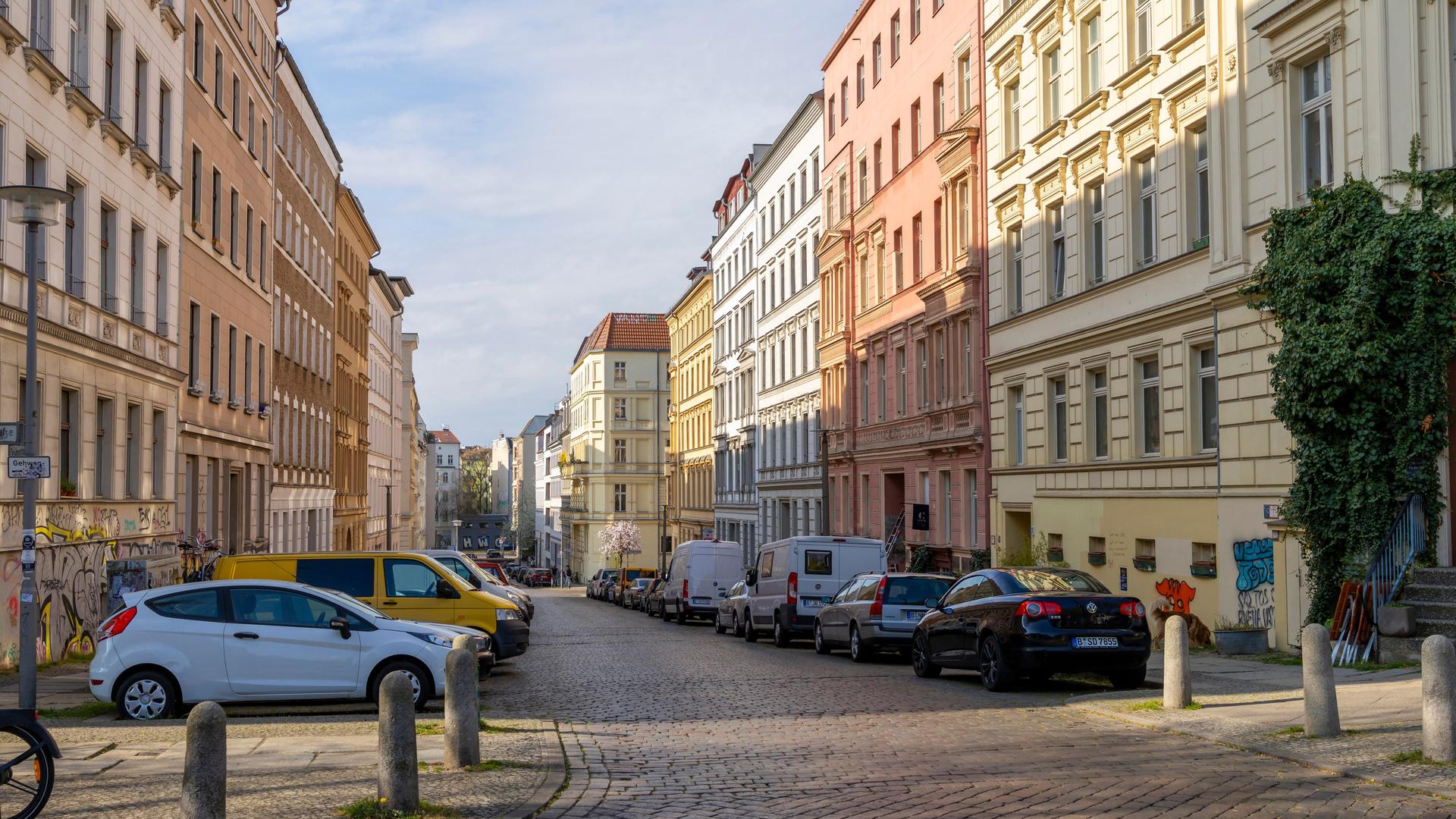 Eine Straße mit schönen Altbauwohnungen in Berlin. Auf der Straße parken ein paar Autos. Vor einem Haus im Vordergrund ist auch ein kleiner, grüner Baum oder Strauch. Eine Straße mit schönen Altbauwohnungen in Berlin. Auf der Straße parken ein paar Autos. Vor einem Haus im Vordergrund ist auch ein kleiner, grüner Baum oder Strauch.
