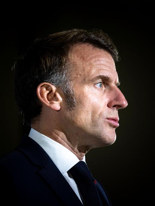 Präsident Emmanuel Macron im Anzug vor dunklem Hintergrund Präsident Emmanuel Macron im Anzug vor dunklem Hintergrund