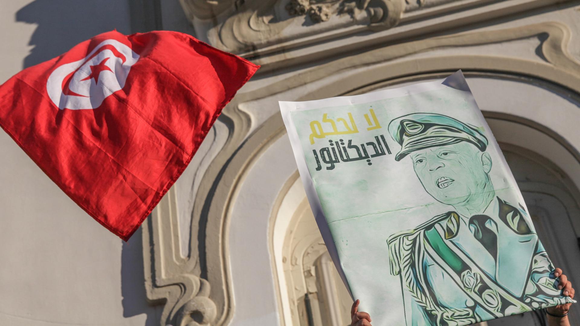 Eine Karikatur des tunesischen Präsidenten Kais Saied in Militäruniform mit der arabischen Aufschrift "Nein zur Herrschaft eines Diktators" neben der tunesischen Flagge. Während einer Demonstration von Anhängern tunesischer Oppositionsparteien und tunesischer zivilgesellschaftlicher Gruppen in Tunis am 22. Juli 2022, um gegen den tunesischen Präsidenten Kais Saied zu protestieren und zum Boykott des bevorstehenden Verfassungsreferendums am 25. Juli aufzurufen. 
