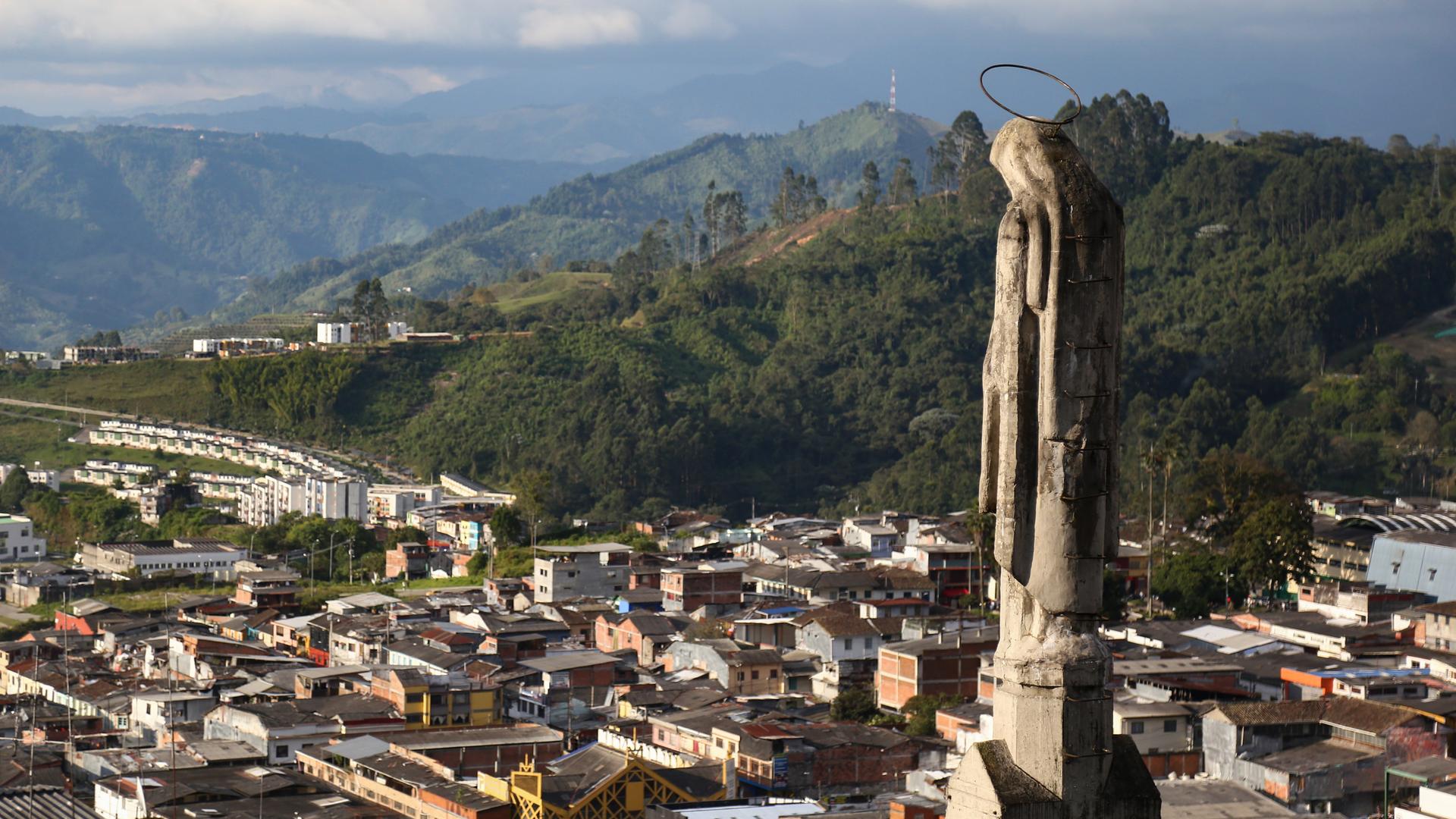 Eine Statute auf der Kathedralbasilika "Unserer Lieben Frau vom Rosenkranz" schaut über die Stadt Manizale, im Hintergrund sind die Berge zu sehen.