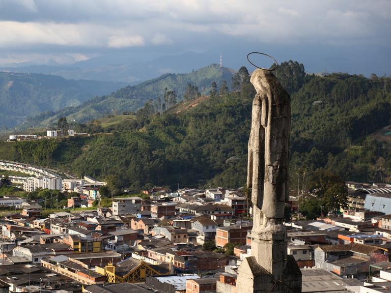 Eine Statute auf der Kathedralbasilika "Unserer Lieben Frau vom Rosenkranz" schaut über die Stadt Manizale, im Hintergrund sind die Berge zu sehen.
