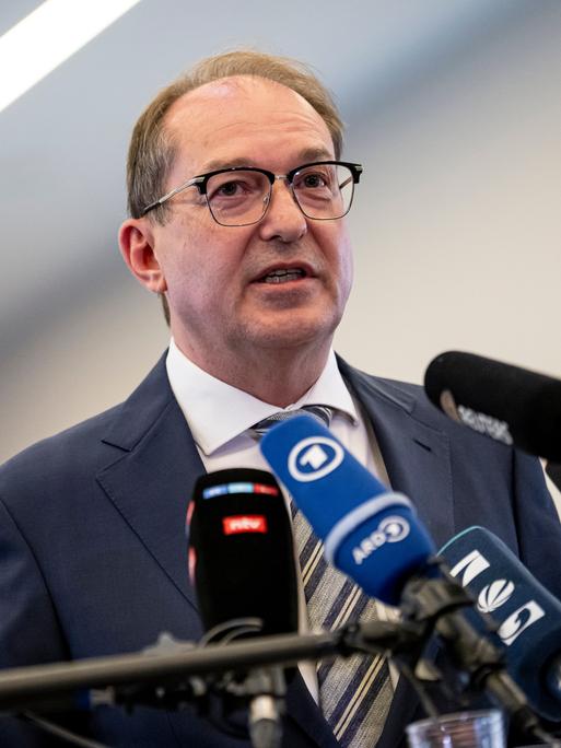 Innenminister Alexander Dobrindt (CSU) steht vor mehreren Mikrofonenn und gibt ein Pressestatement.