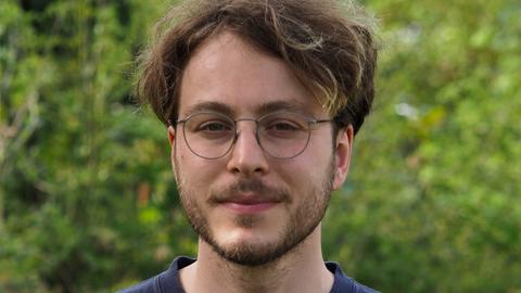 Marco Ott trägt eine Brille und Bart, steht in einem grünen Garten und schaut freundlich in die Kamera.