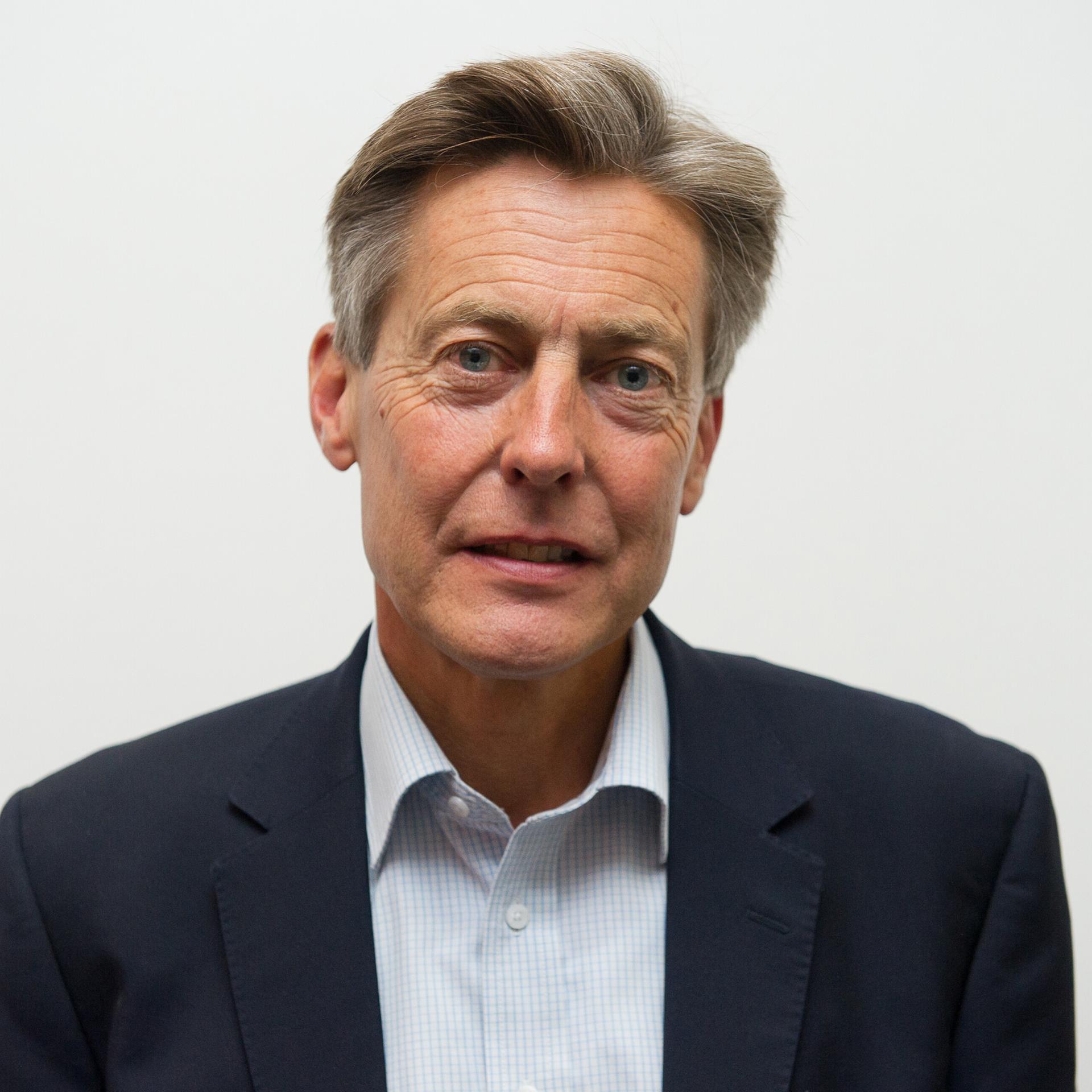 Ben Bradshaw steht vor einem weißen Hintergrund. Er trägt ein Hemd und ein Jackett.