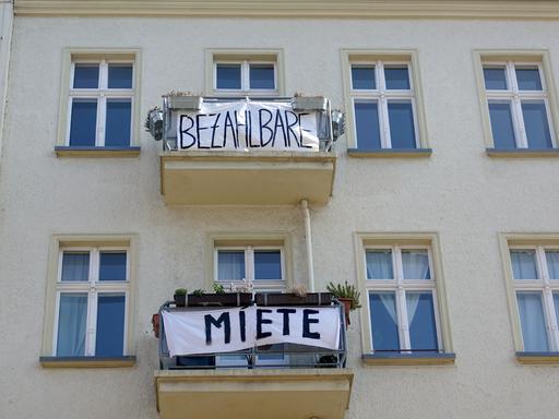 An den Balkonen eines Wohnhauses sind Protestplakate mit verschiedenen Slogans wie "Bezahlbare" und "Miete" angebracht.