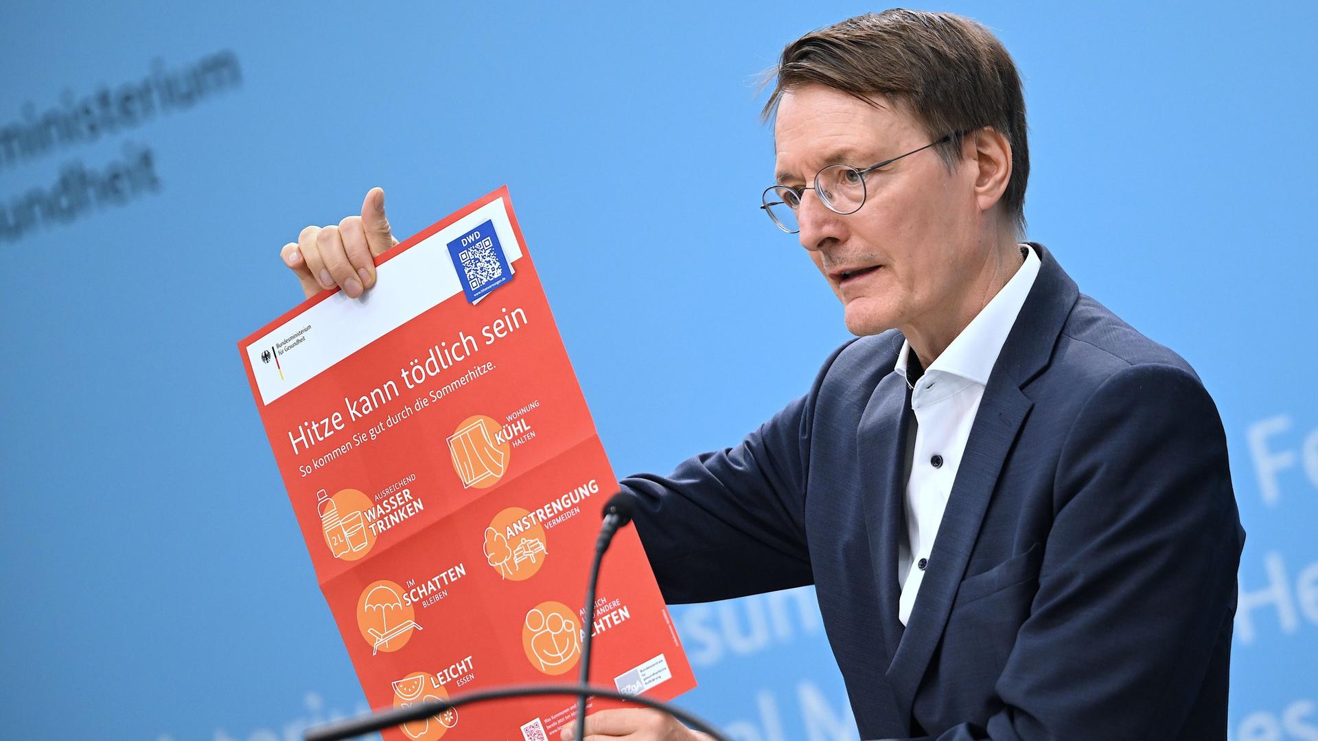 Berlin: Bundesgesundheitsminister Karl Lauterbach (SPD) hält ein Plakat mit der Aufschrift "Hitze kann tödlich sein" während einer Pressekonferenz zum Thema Hitzeschutz. 