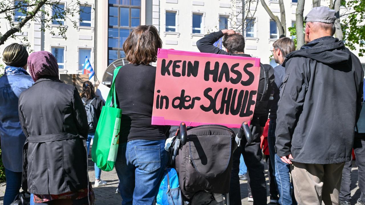 Frauen und Männer bei einer Demonstration gegen Rechtsextremismus an Schulen. Im Vordergrund ein Schild mit der Aufschrift "Kein Hass in der Schule"