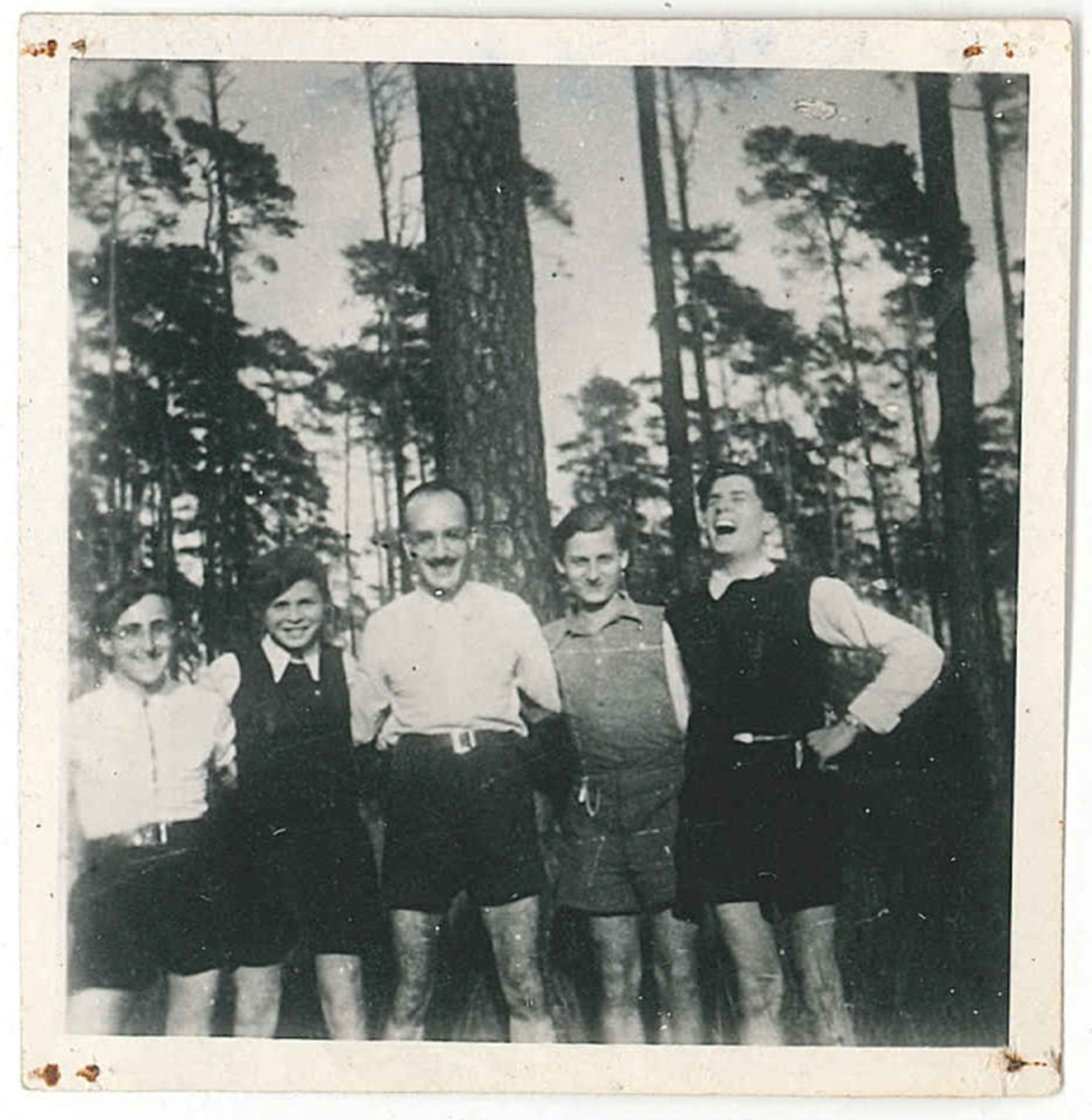 Fünf Männer stehen im Grunewald in Berlin und posieren für das Foto, sie haben sich beieinander eingehakt. Es ist in Schwarz-Weiß.
