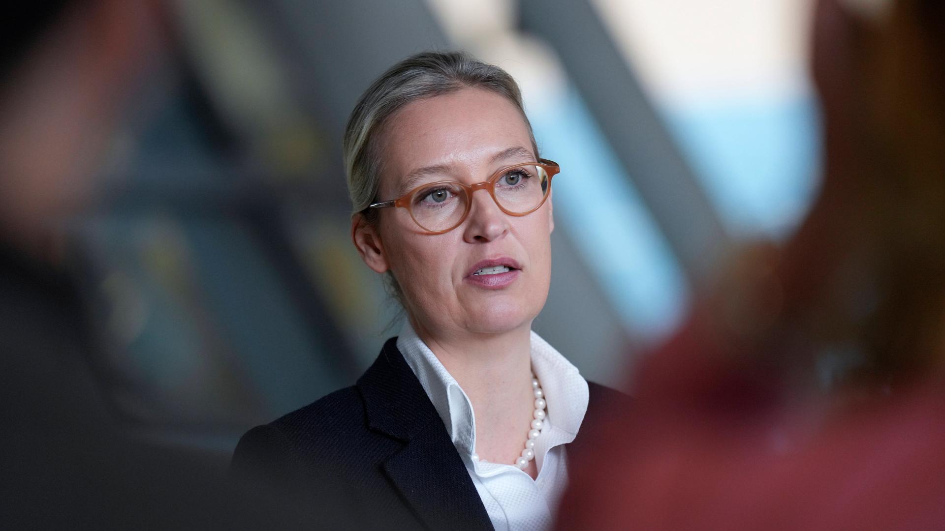 EIn Foto der AfD-Chefin Alice Weidel in Berlin. Sie trägt eine braune Brille, weißes Hemd, Perlenkette und darüber einen schwarzen Blazer.