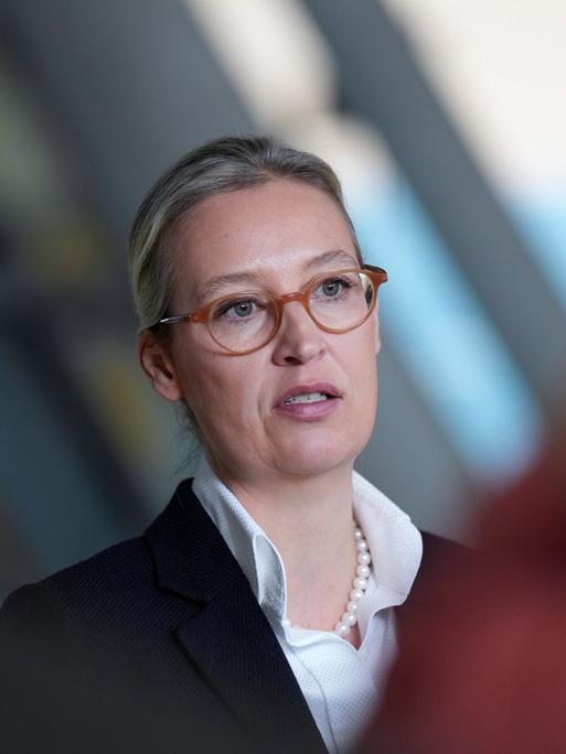 EIn Foto der AfD-Chefin Alice Weidel in Berlin. Sie trägt eine braune Brille, weißes Hemd, Perlenkette und darüber einen schwarzen Blazer.