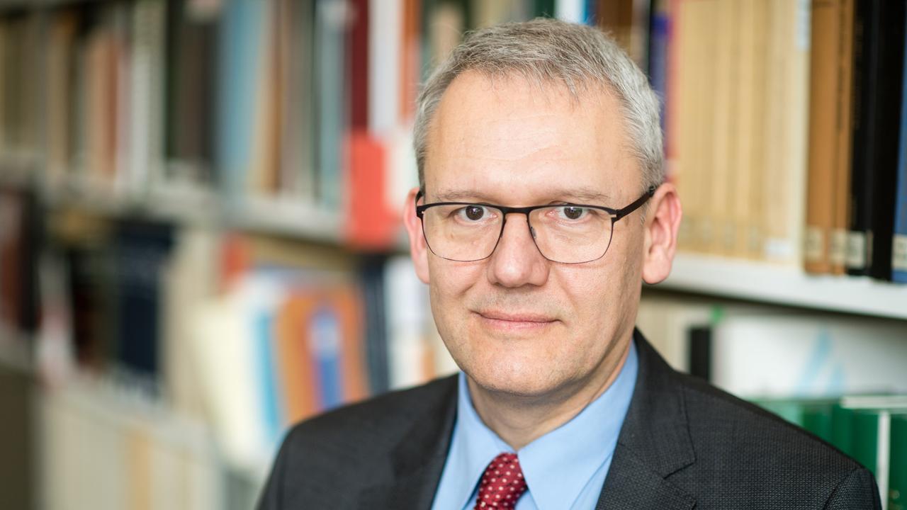 Der Historiker Andreas Wirsching steht vor einer Bücherwand.