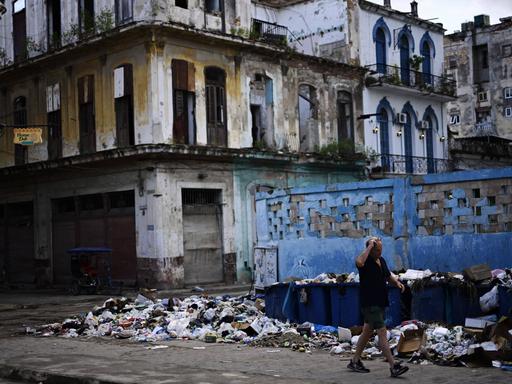 In einer Gasse in Havanna stapelt sich Müll vor einer Haus mit verfallener Fassade.