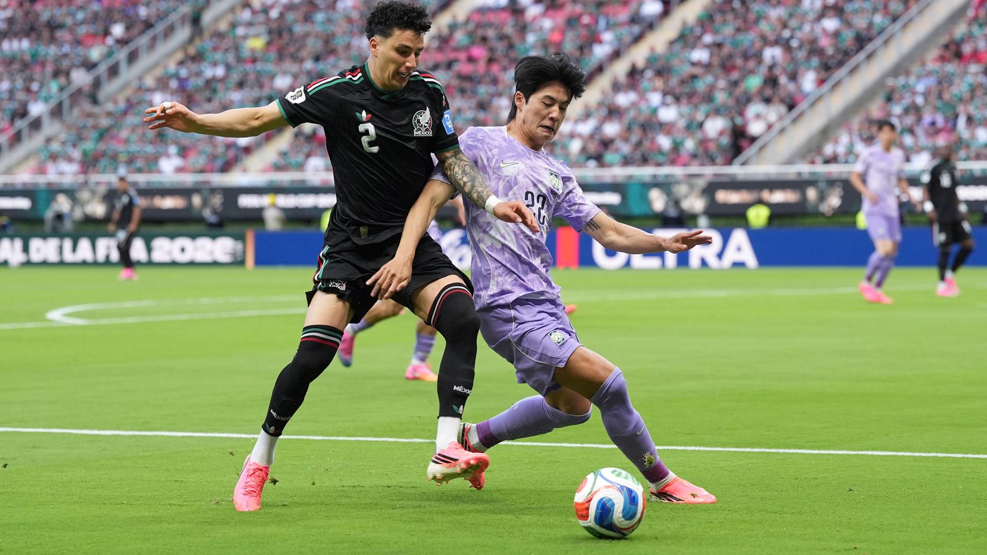 Ein mexikanischer und ein südkoreanischer Fußballer kämpfen um den Ball.