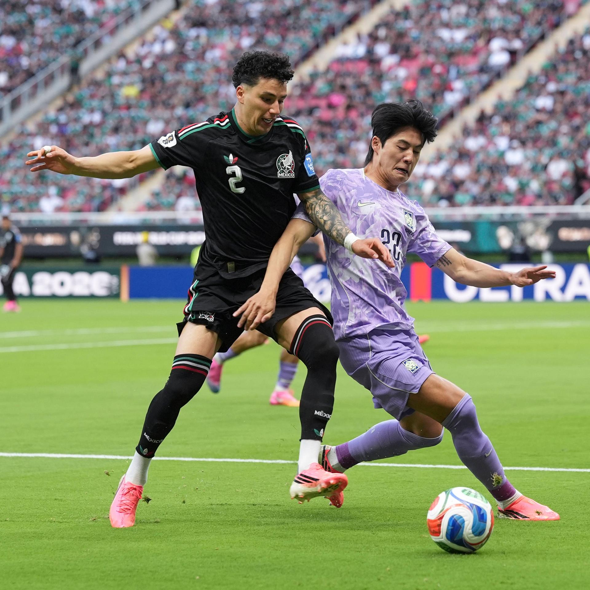 Ein mexikanischer und ein südkoreanischer Fußballer kämpfen um den Ball.