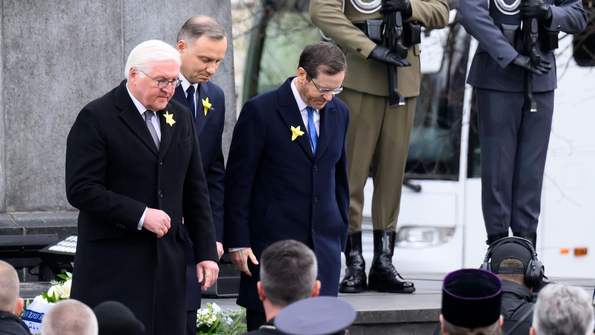 Gedenk-Feier in der Stadt Warschau in dem Land Polen: Bundespräsident Frank-Walter Steinmeier (links) steht neben Izchak Herzog (Präsident von dem Land Israel) und Andrzej Duda (Präsident von dem Land Polen). Sie verneigen sich.