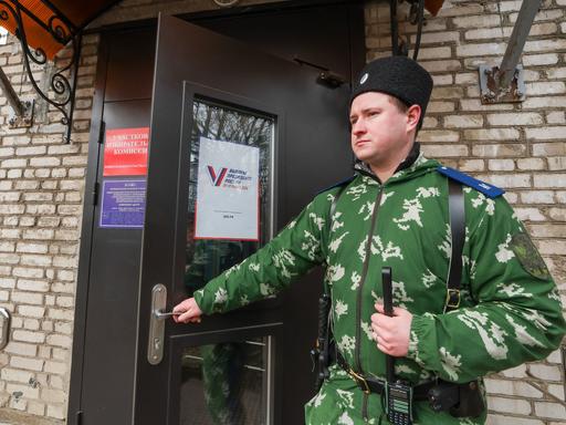  Ein militärisch anmutender  Wächter steht am Eingang eines Wahllokal