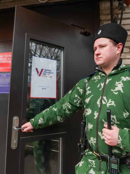  Ein militärisch anmutender  Wächter steht am Eingang eines Wahllokal